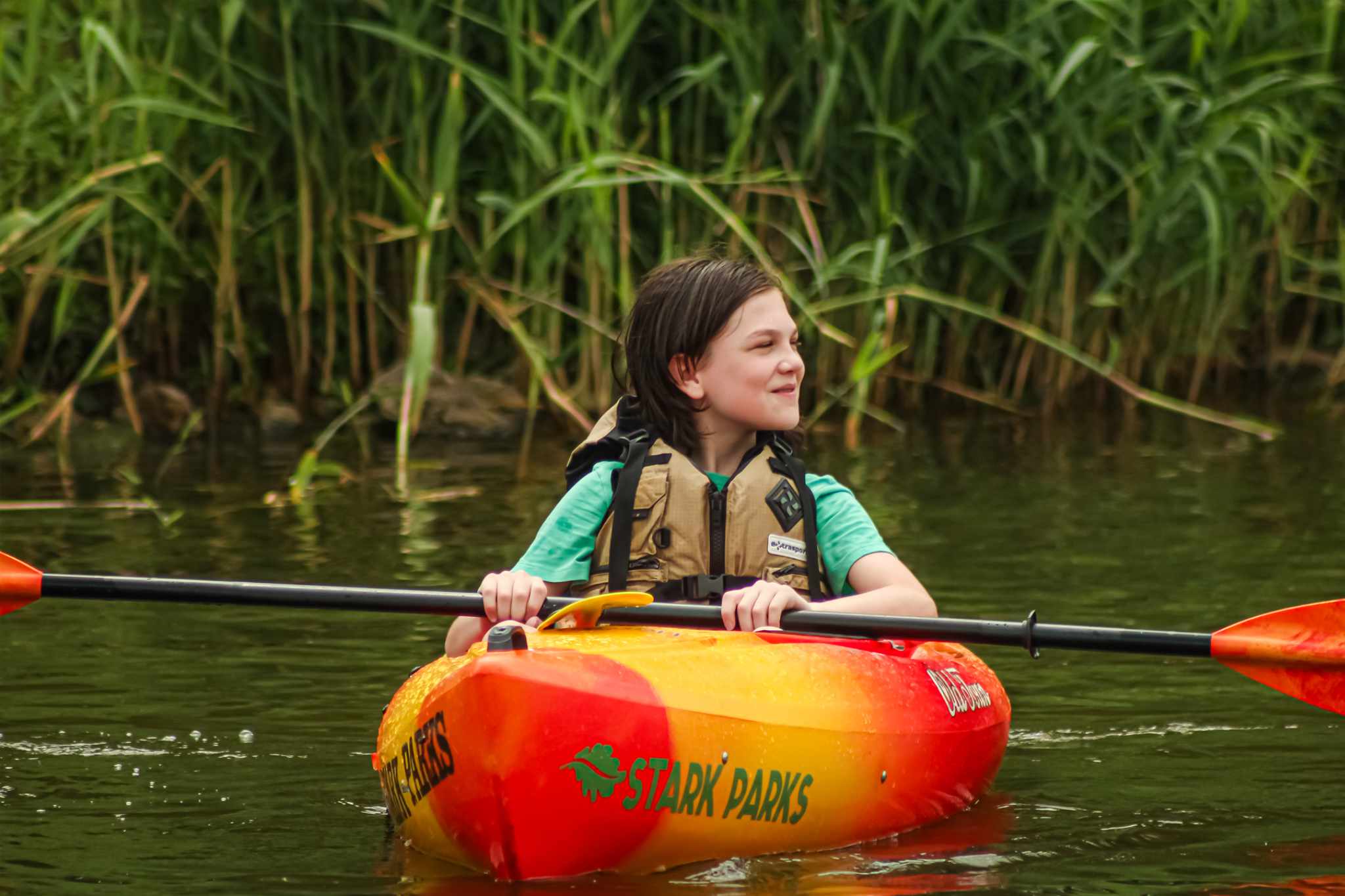 Kid in kayak with paddle floating on water